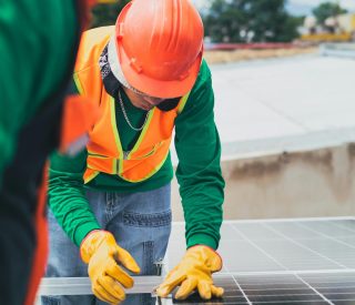pexels-photo-8853507-8853507 Worker in safety gear installing solar panels on a rooftop.